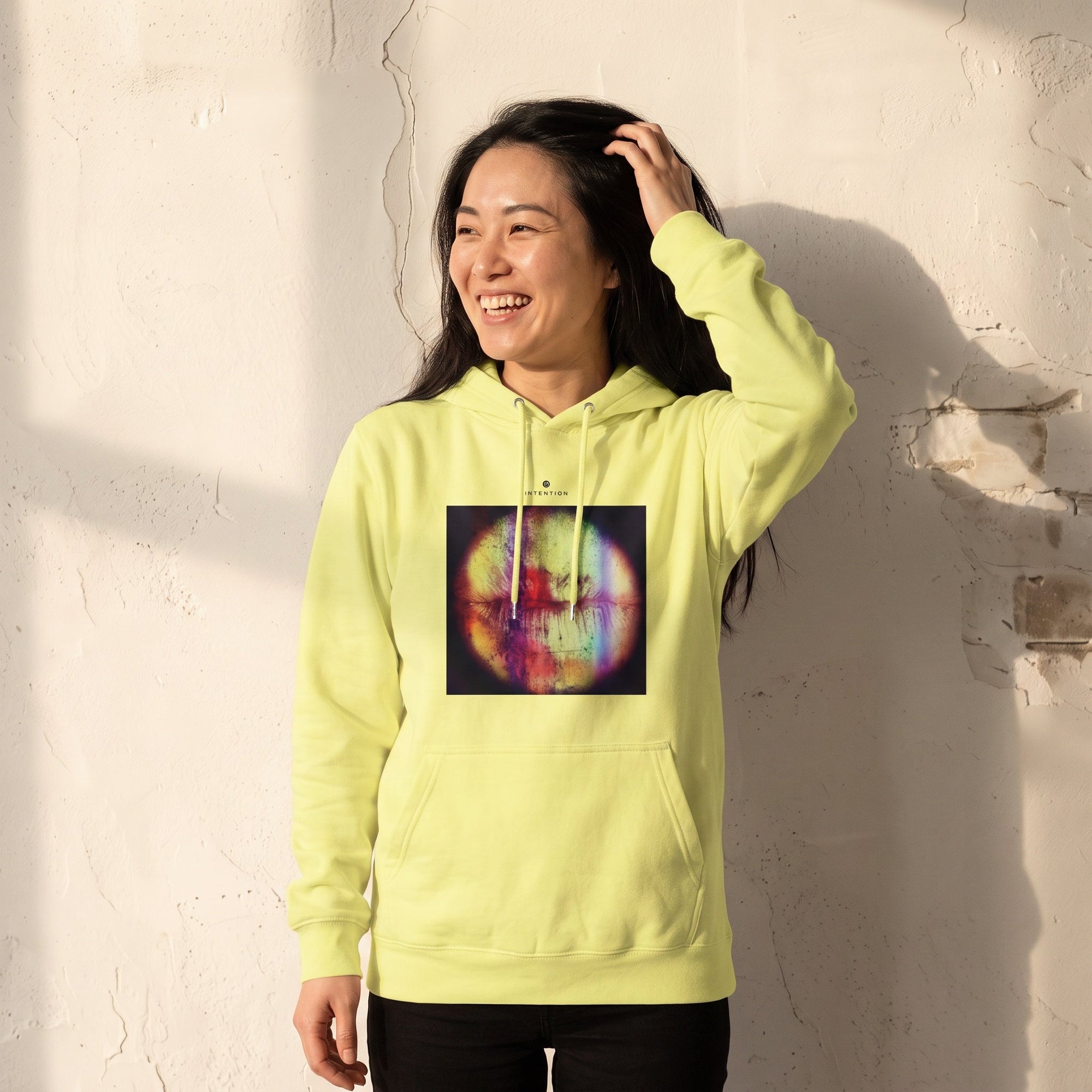 Love - "Chromatic Kiss" Light Yellow Hoodie worn against a sunlit plaster wall
