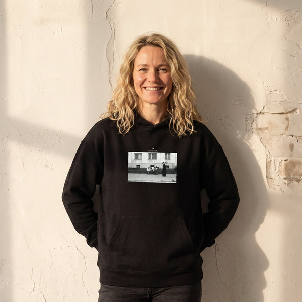 Oneness - "The Urban Matrix" Black Hoodie worn against a sunlit plaster wall