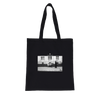 This black tote bag with long handles features an art print—a black and white photo of two people on a sidewalk in front of a building—with "INTENTION" printed above, crafted with conscious fashion in mind.