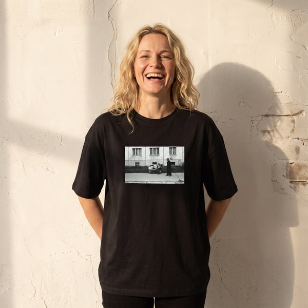 Oneness - "The Urban Matrix" Deep Black T-shirt worn against a sunlit plaster wall
