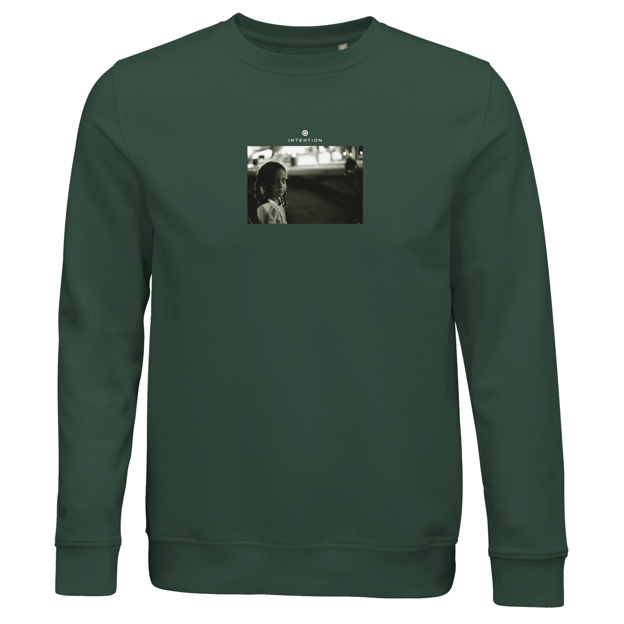A bottle green crewneck sweatshirt features a centered black-and-white photo art print of a woman looking at the camera with text above, designed for conscious fashion enthusiasts.