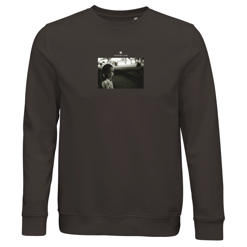 A deep charcoal grey crewneck sweatshirt with a small, centered black-and-white art print of a woman standing outdoors at night and "TOKYO 1995" above the image—perfect for fans of conscious fashion.