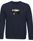 A French Navy sweatshirt featuring a small, centered black-and-white photo print on the chest of a person outdoors at night, with text above the image for a bold, thoughtful fashion statement.