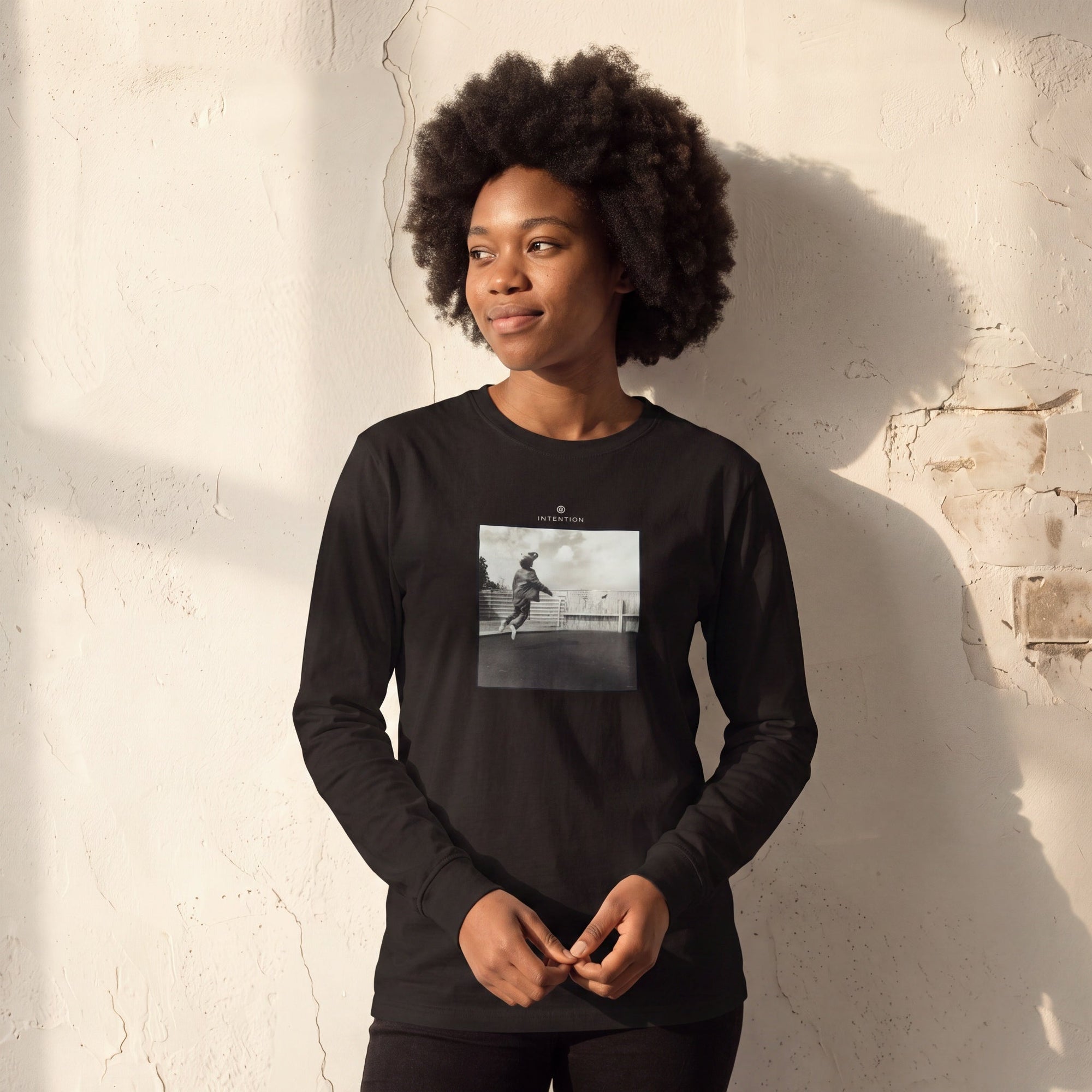 Transcendence - "Ready to Fly" Deep Black Long Sleeve worn against a sunlit plaster wall
